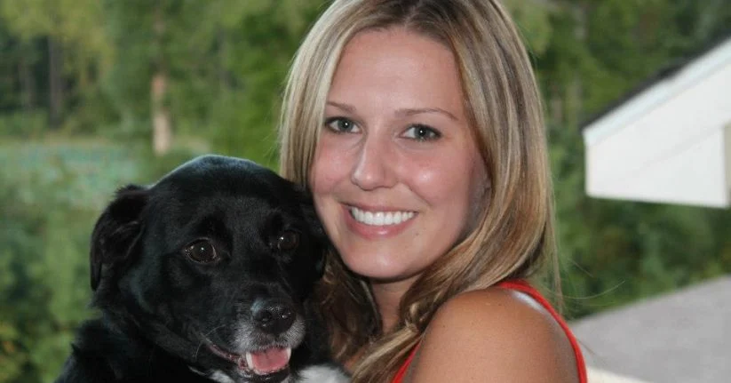 Melissa hugging her black dog